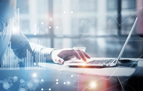 En kostymklädd arm och vänster hand som skriver på en laptop